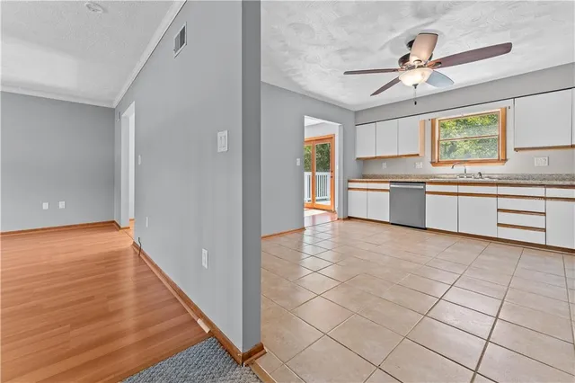 a large white kitchen with a stove a sink dishwasher and a refrigerator with wooden floor
