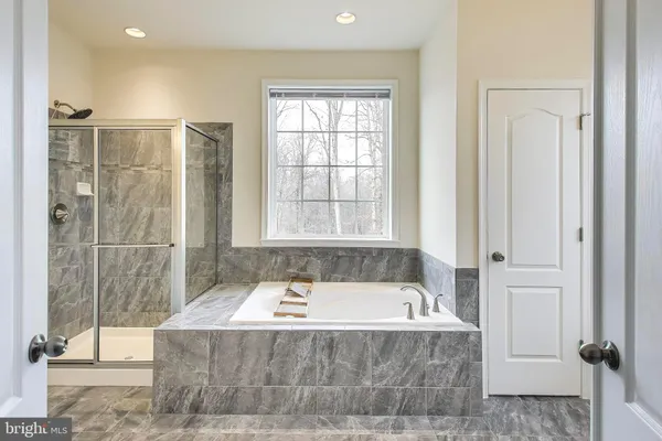 a bathroom with a granite countertop tub sink and mirror