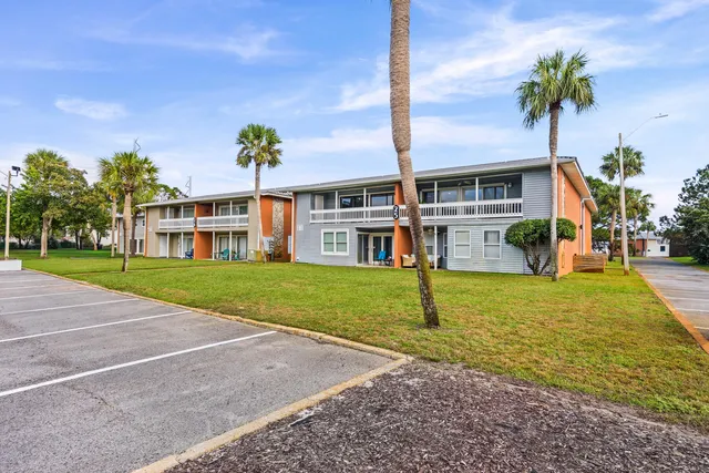 a view of a big house with a big yard and palm trees