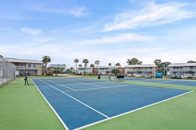 a view of a tennis ground with large trees