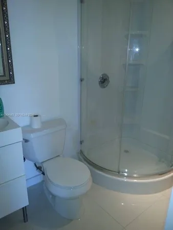 a white toilet next to a shower