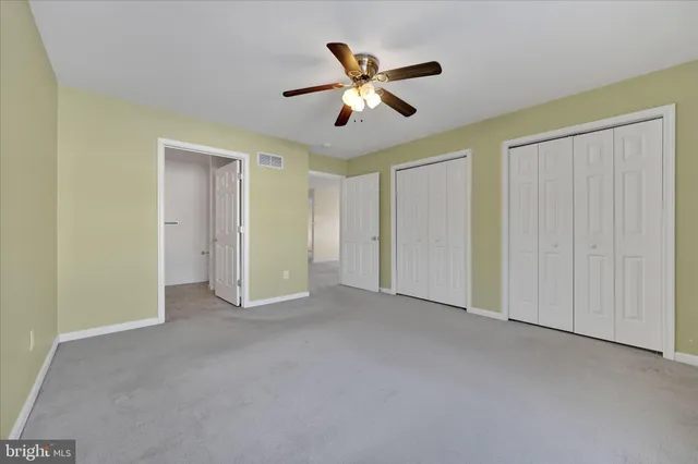 a view of an empty room and chandelier fan