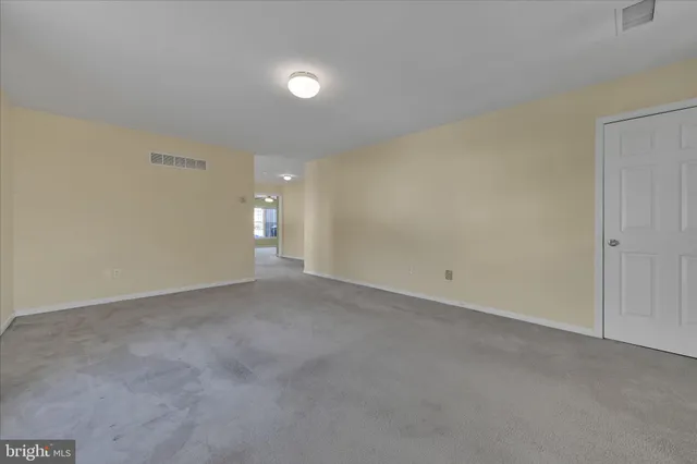 a view of an empty room and chandelier fan