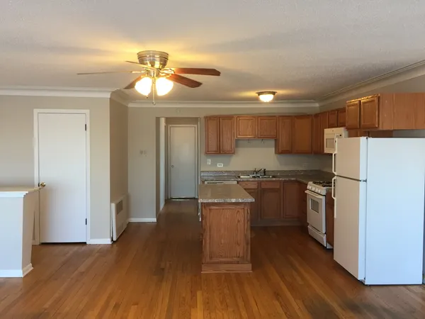 a kitchen with kitchen island granite countertop a refrigerator oven a sink dishwasher and white cabinets with wooden floor