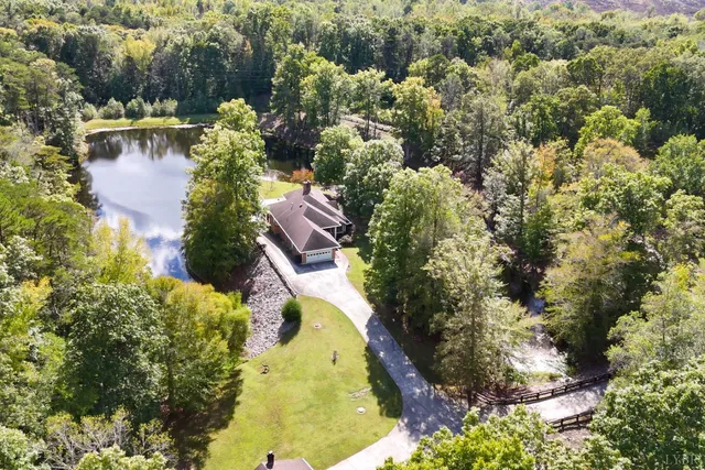 an aerial view of residential house with outdoor space and trees all around