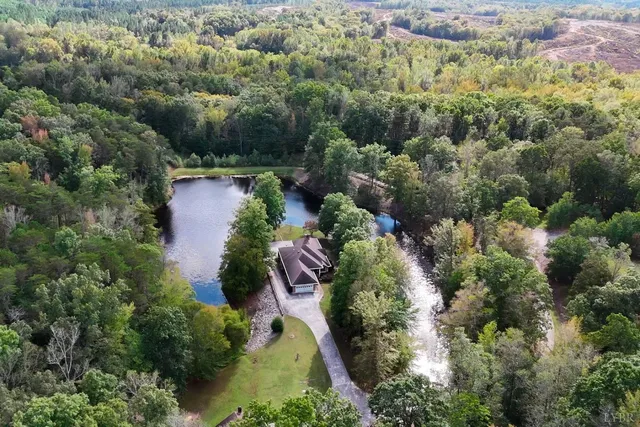 an aerial view of residential house with outdoor space and trees all around