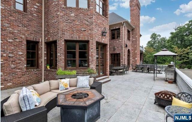 35 Timberline Drive Alpine, NJ 07620 - Photo 30 of 37 a view of a patio with couches table and chairs under an umbrella with a fire pit