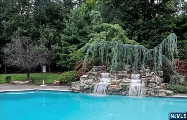 35 Timberline Drive Alpine, NJ 07620 - Photo 34 of 37 a view of a swimming pool with lawn chairs and a big yard