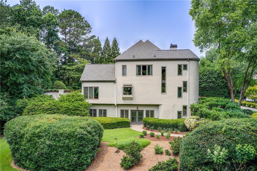 115 Cross Roads Court Atlanta, GA 30327 - Photo 50 of 55 a view of a white house next to a yard with plants and large trees