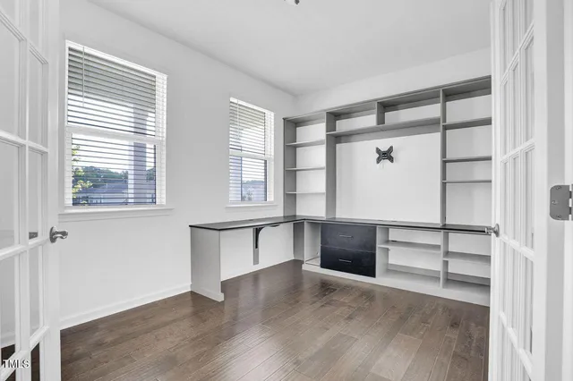 a view of an empty room with a window and wooden floor