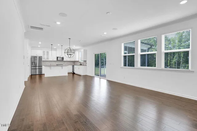 a view of a kitchen with kitchen island wooden floors and stainless steel appliances