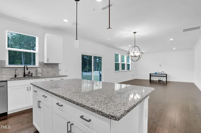 a kitchen with stainless steel appliances granite countertop kitchen island a stove a sink a center island and windows
