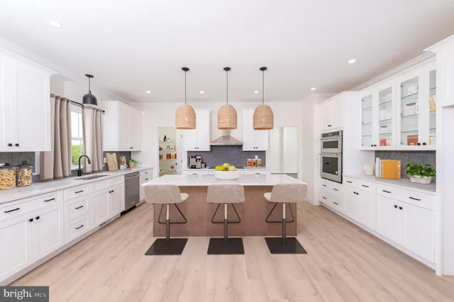a large kitchen with kitchen island a island a sink a stove and a wooden floors