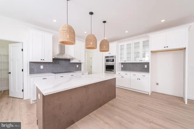 a large kitchen with kitchen island a stove a sink a center island and wooden floor