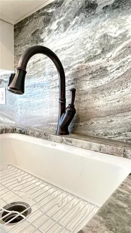 a view of kitchen with granite countertop sink and cabinets
