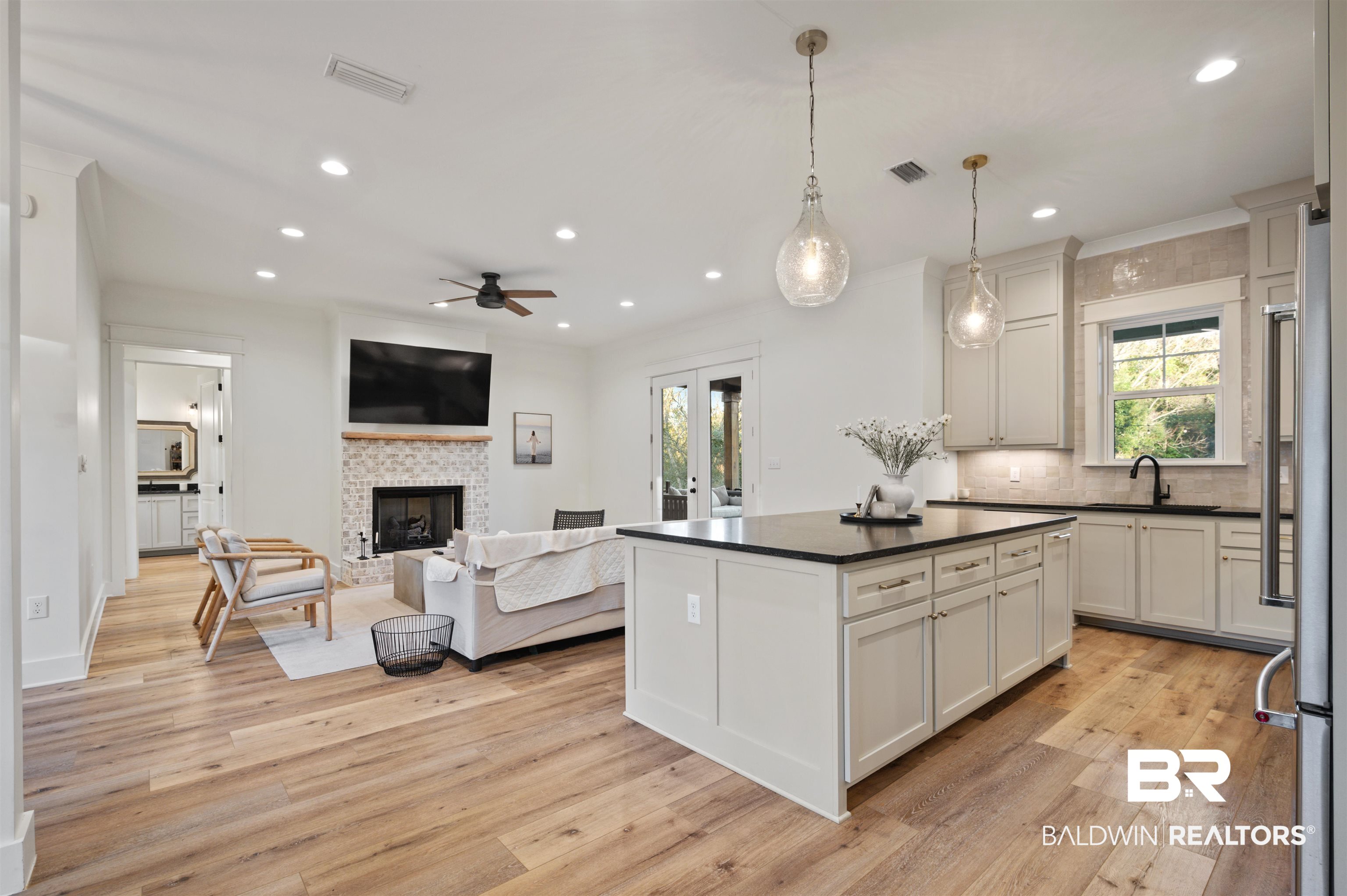 312 Pecan Ridge Boulevard Fairhope, AL 36532 - Photo 16 of 43 Kitchen with white cabinets, decorative light fixtures, sink, ceiling fan, and a tiled fireplace