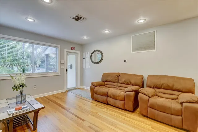 a living room with furniture a wooden floor and a large window