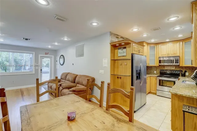 a living room with stainless steel appliances furniture and a kitchen view