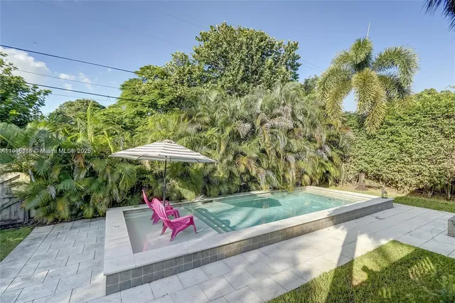 a backyard of a house with table and chairs under an umbrella