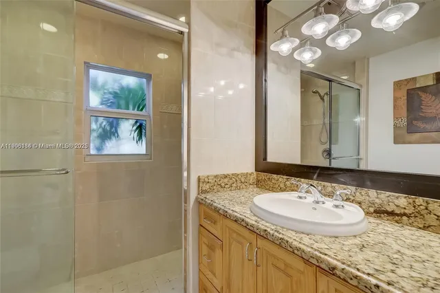 a bathroom with a granite countertop sink a mirror and a shower