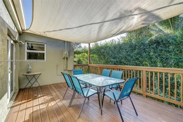 a view of a roof deck with table and chairs under an umbrella with potted plants