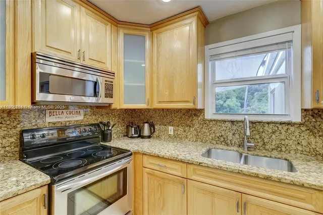 a kitchen with granite countertop a sink stainless steel appliances and cabinets