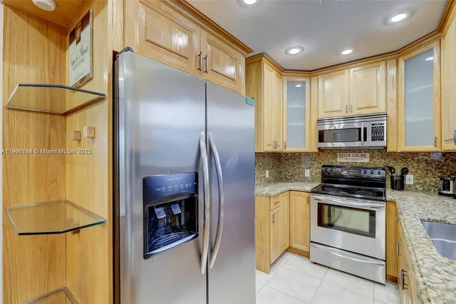 a kitchen with stainless steel appliances granite countertop a refrigerator a stove and a sink with wooden floor