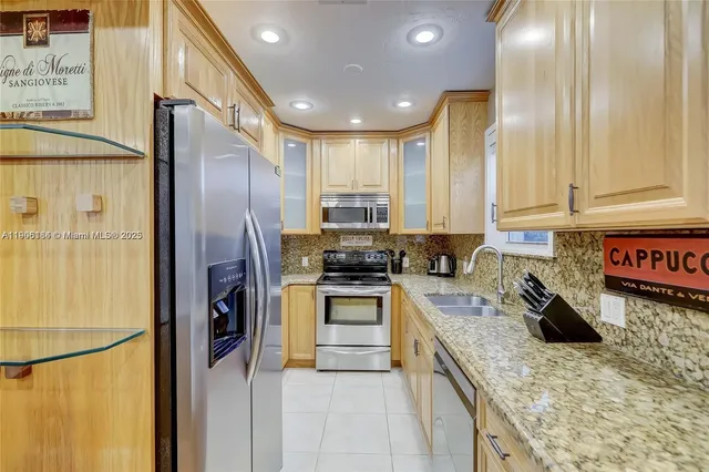 a kitchen with stainless steel appliances granite countertop a refrigerator a stove and a sink
