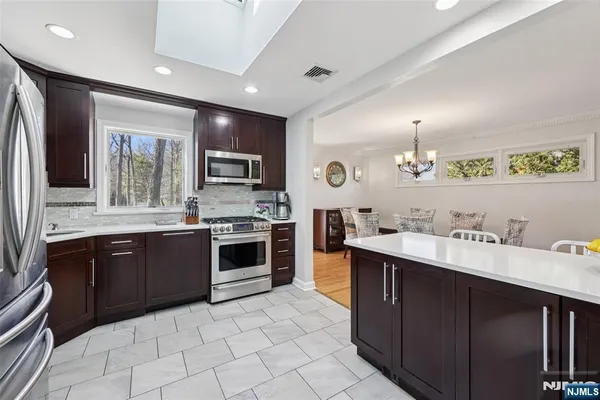 a large kitchen with stainless steel appliances granite countertop a sink and dishwasher a stove top oven with wooden floor