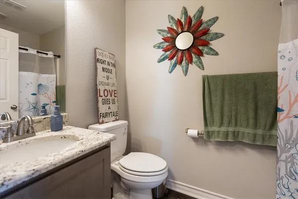 a bathroom with a granite countertop sink a toilet and a shower