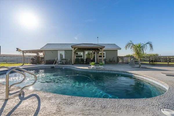 a view of a house with backyard patio and swimming pool