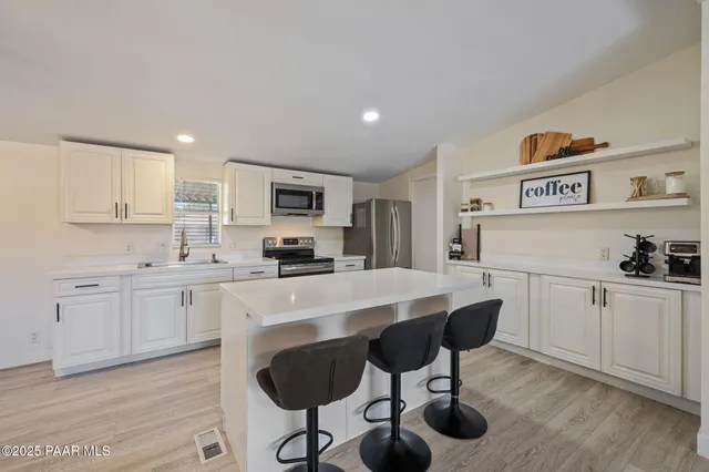 a kitchen with stainless steel appliances a stove a sink cabinets and a refrigerator