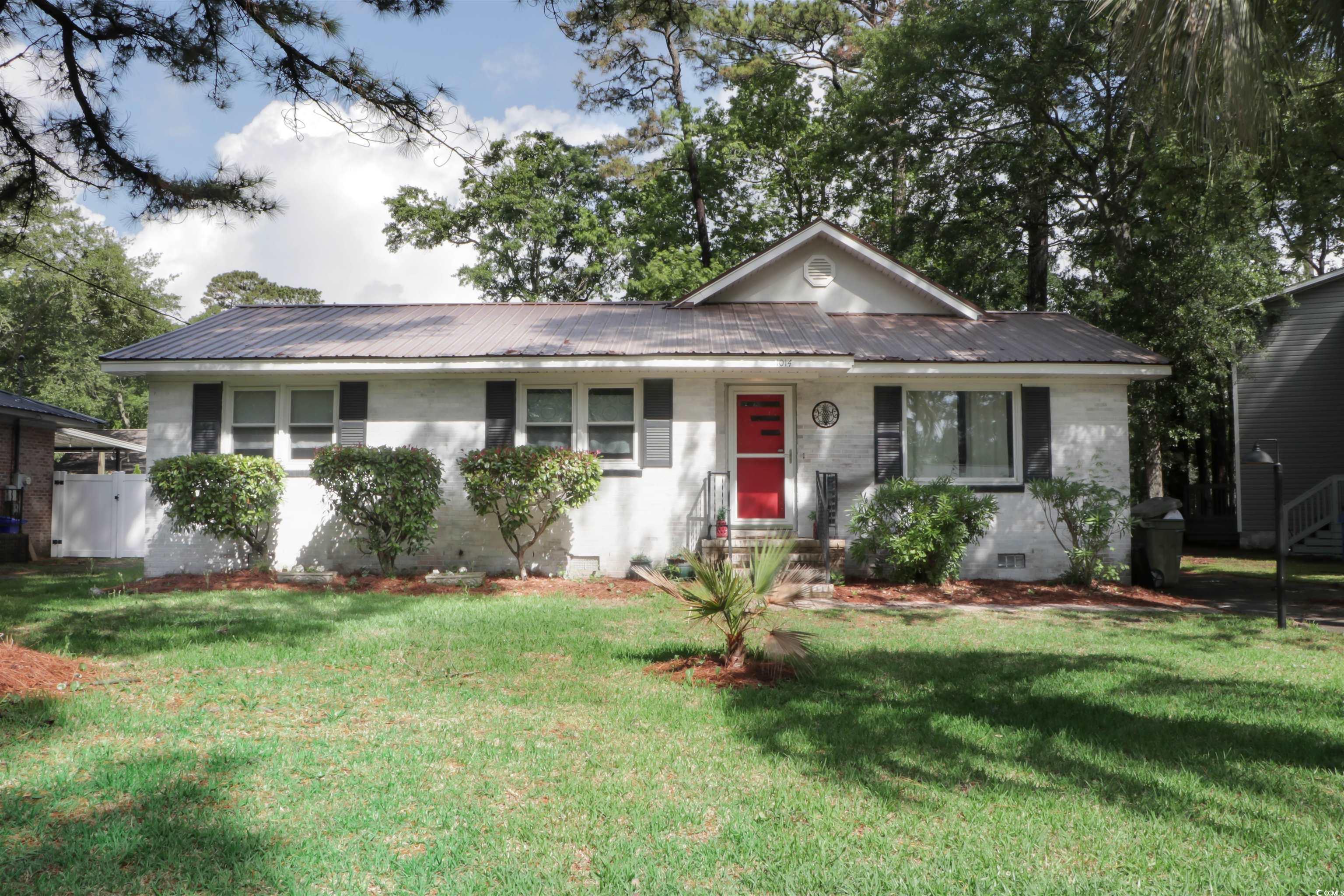 Ranch-style home with metal roof, a front yard, and crawl space
