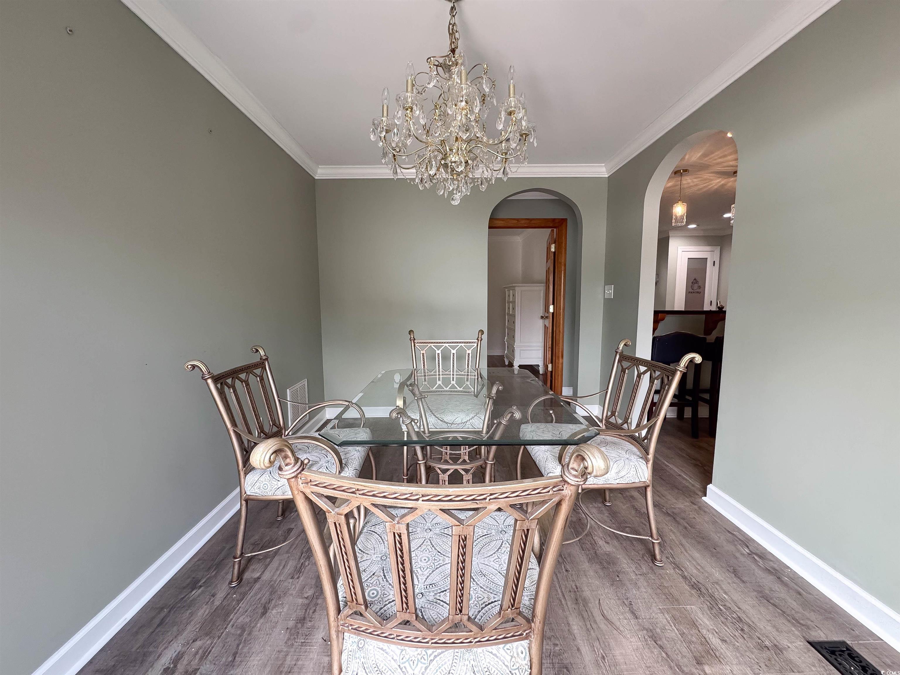 1014 Bay Drive Surfside Beach, SC 29575 - Photo 13 of 27 Dining area featuring wood finished floors, a chandelier, arched walkways, baseboards, and crown molding