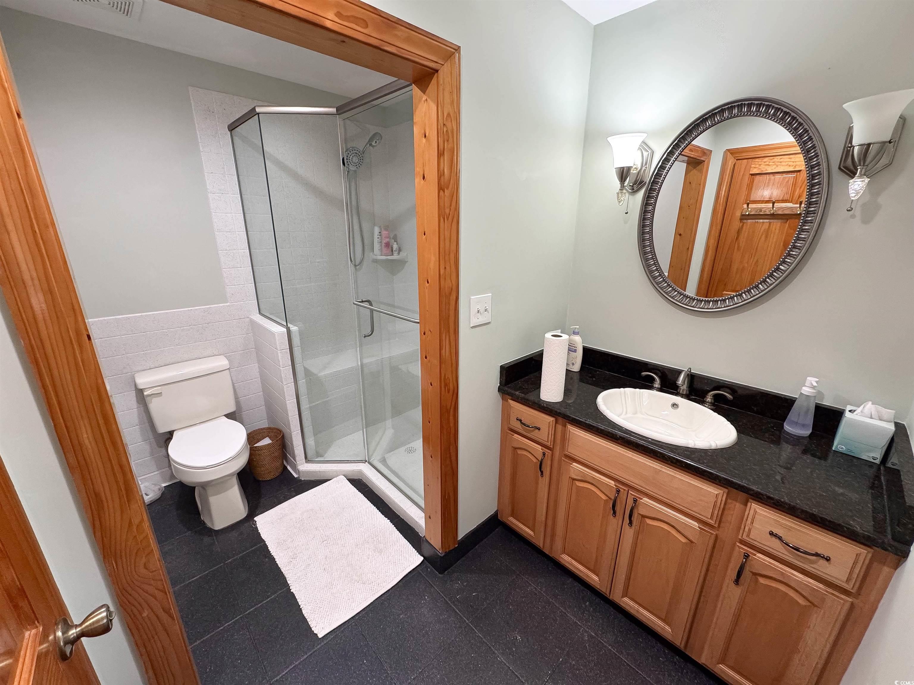 1014 Bay Drive Surfside Beach, SC 29575 - Photo 14 of 27 Bathroom featuring tile walls, toilet, a shower stall, vanity, and wainscoting
