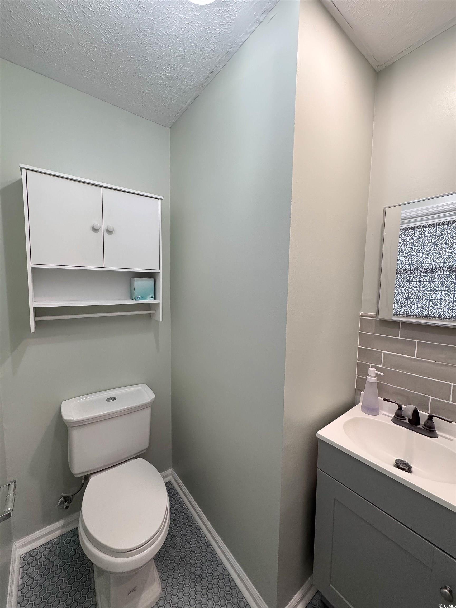 1014 Bay Drive Surfside Beach, SC 29575 - Photo 17 of 27 Half bathroom with tile patterned flooring, toilet, vanity, a textured ceiling, and baseboards