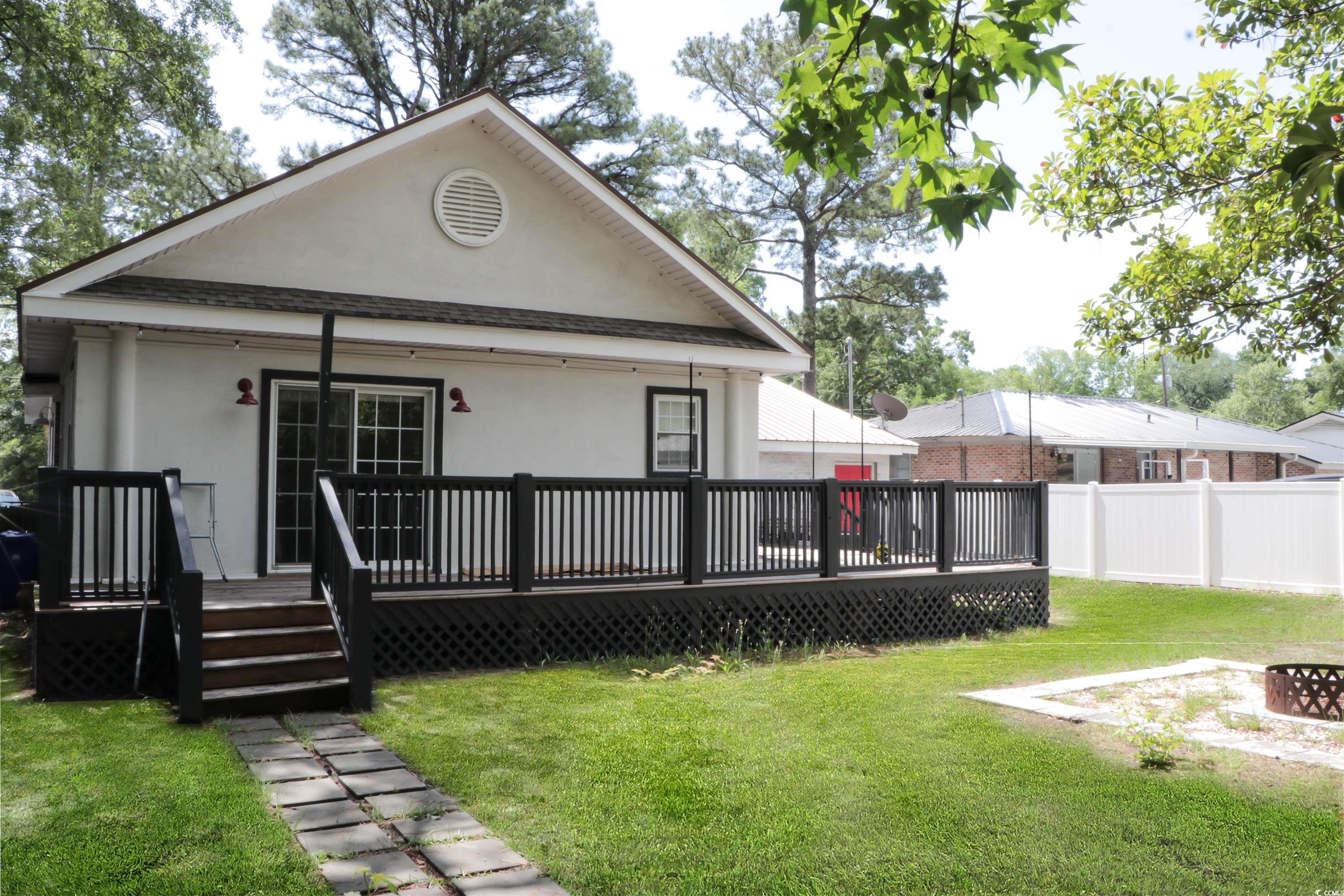 1014 Bay Drive Surfside Beach, SC 29575 - Photo 26 of 27 Back of house with stucco siding, a wooden deck, roof with shingles, and an outdoor fire pit