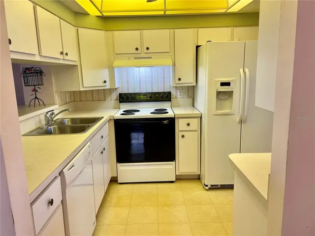 a kitchen with stainless steel appliances granite countertop a sink a stove a refrigerator a cabinets and a window