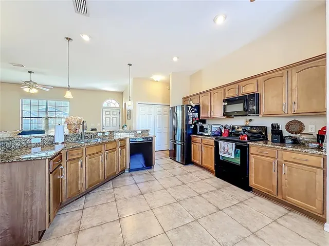 a kitchen with stainless steel appliances granite countertop a stove top oven a sink dishwasher and a refrigerator