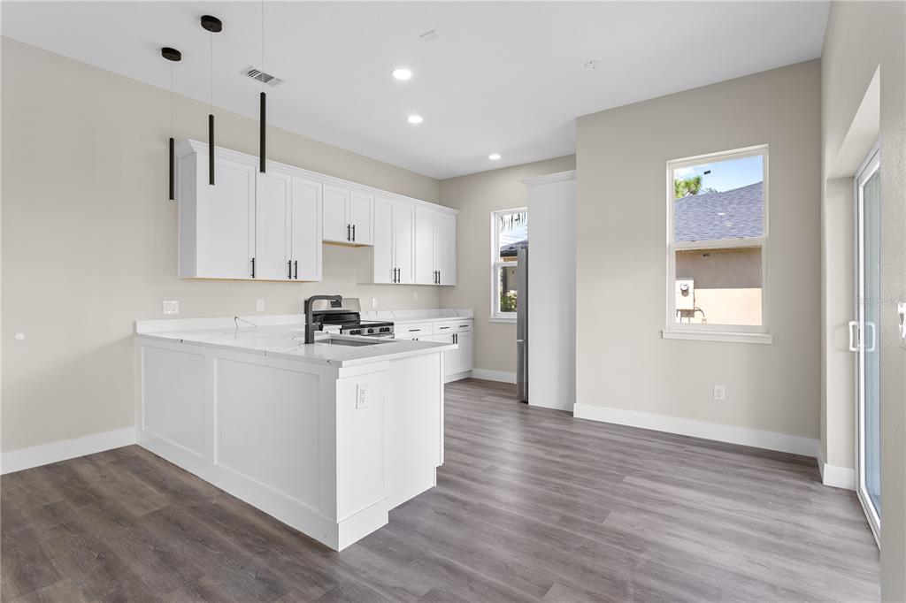 33328 County Road 473 Leesburg, FL 34788 - Photo 7 of 28 a kitchen with stainless steel appliances granite countertop a refrigerator a sink dishwasher a stove and white countertops with wooden floor