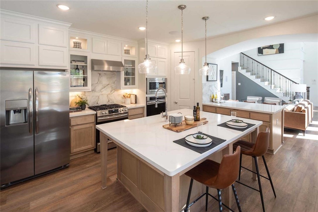 a kitchen with stainless steel appliances kitchen island granite countertop a dining table chairs and refrigerator