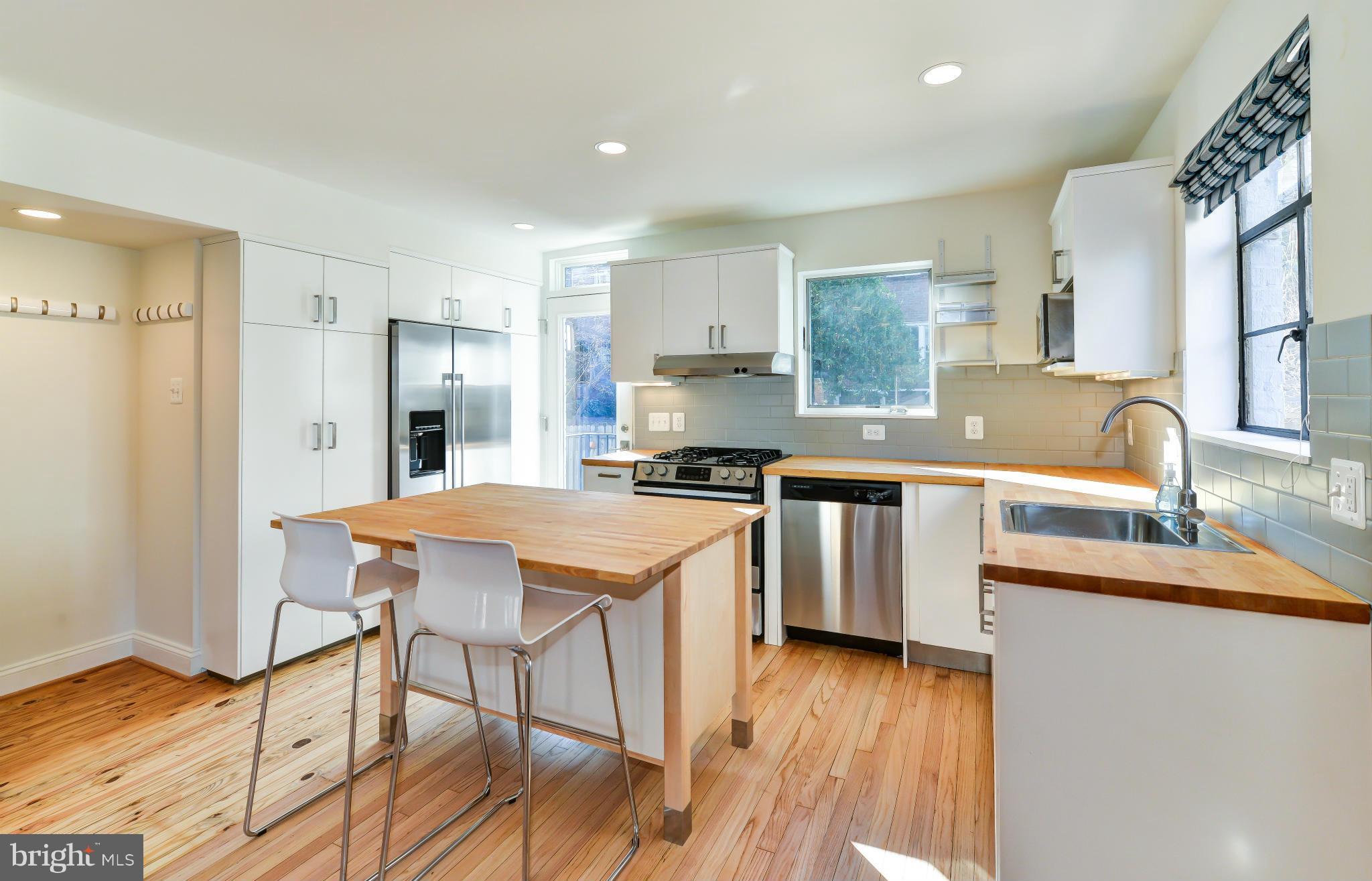 1138 Portner Road Alexandria, VA 22314 - Photo 3 of 30 a kitchen with stainless steel appliances granite countertop a sink a stove a refrigerator and island with wooden floor