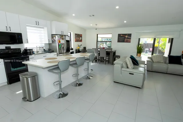 a living room with furniture a flat screen tv and kitchen view
