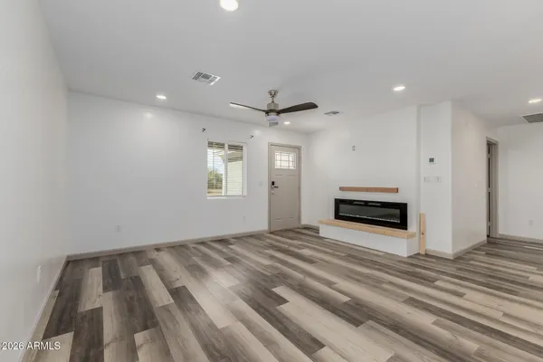 a view of empty room with wooden floor and ceiling fan