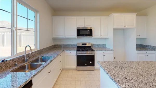 a kitchen with granite countertop a sink a counter top space appliances and cabinets
