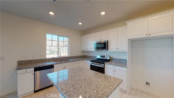 a kitchen with granite countertop a stove a sink and a microwave