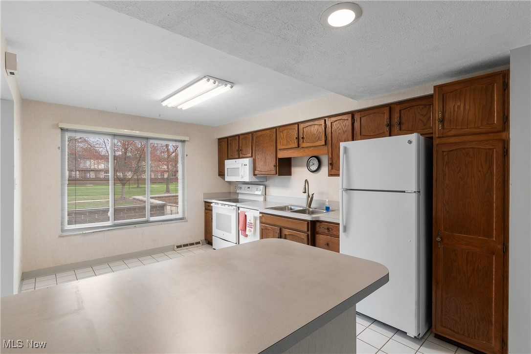 6462 State Road, Unit 4 Parma, OH 44134 - Photo 15 of 42 Kitchen with a sink, visible vents, white appliances, brown cabinets, and light countertops