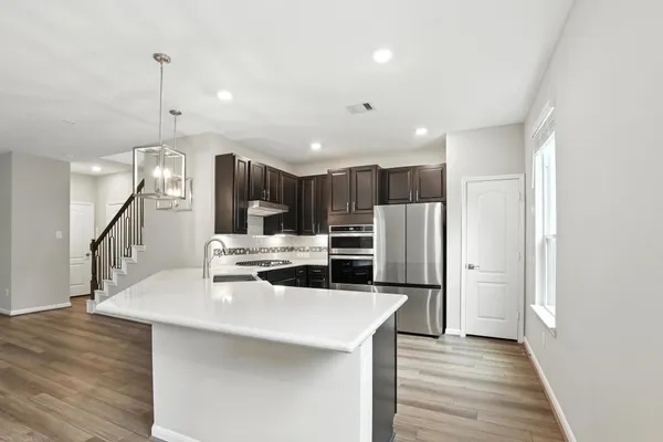 a kitchen with stainless steel appliances kitchen island granite countertop a refrigerator a sink and a stove