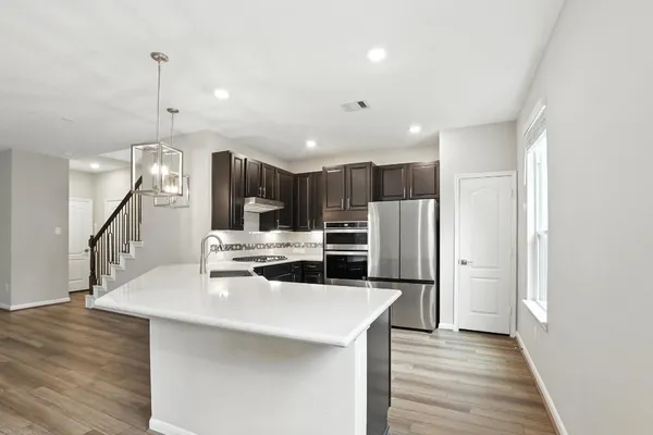 a kitchen with stainless steel appliances kitchen island granite countertop a refrigerator a sink and a stove