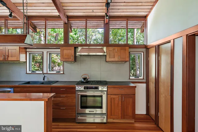 a kitchen with stainless steel appliances granite countertop a sink a stove and a wooden floors